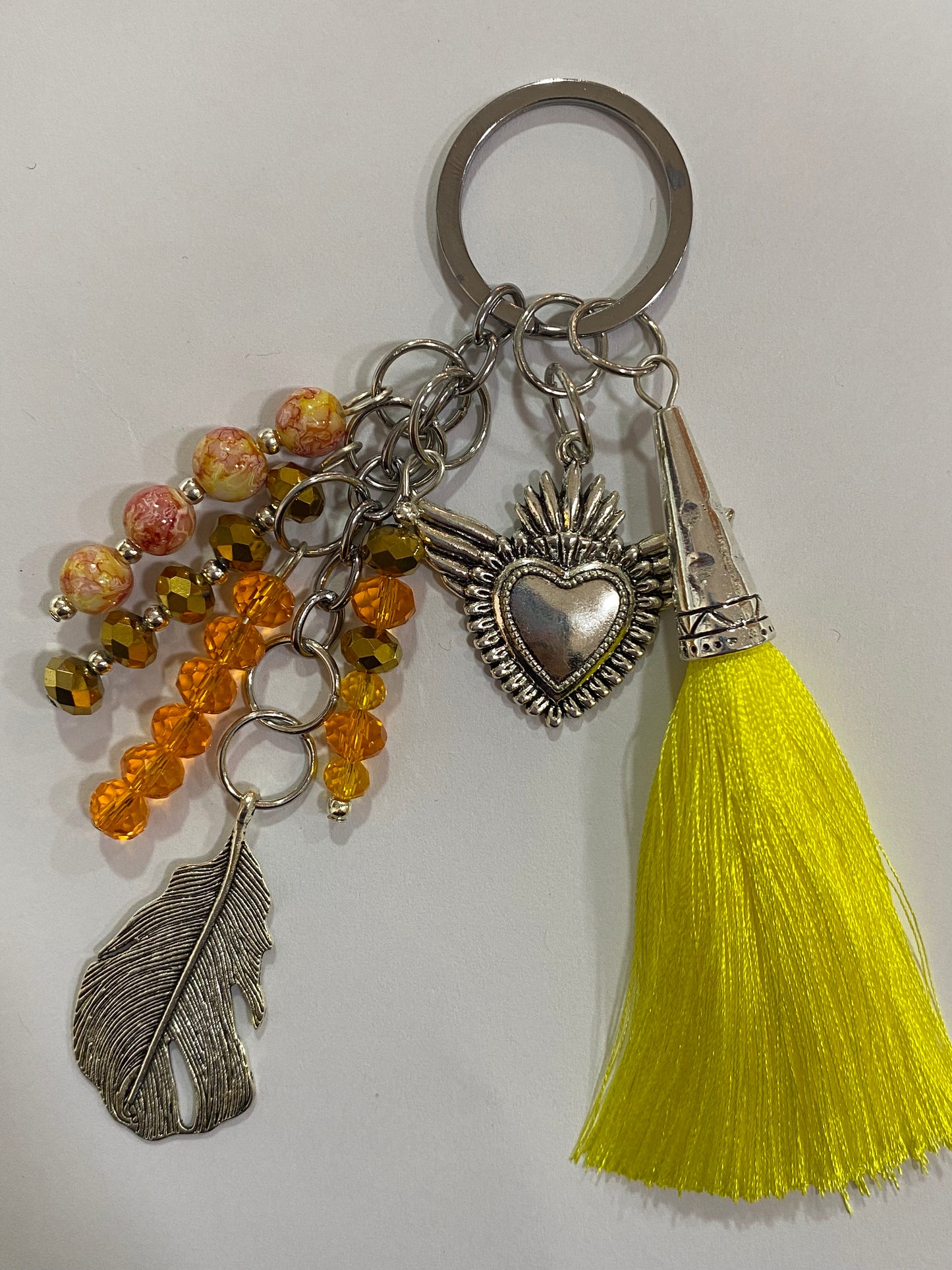 Llavero en tonos amarillos con corazón y pluma plateados