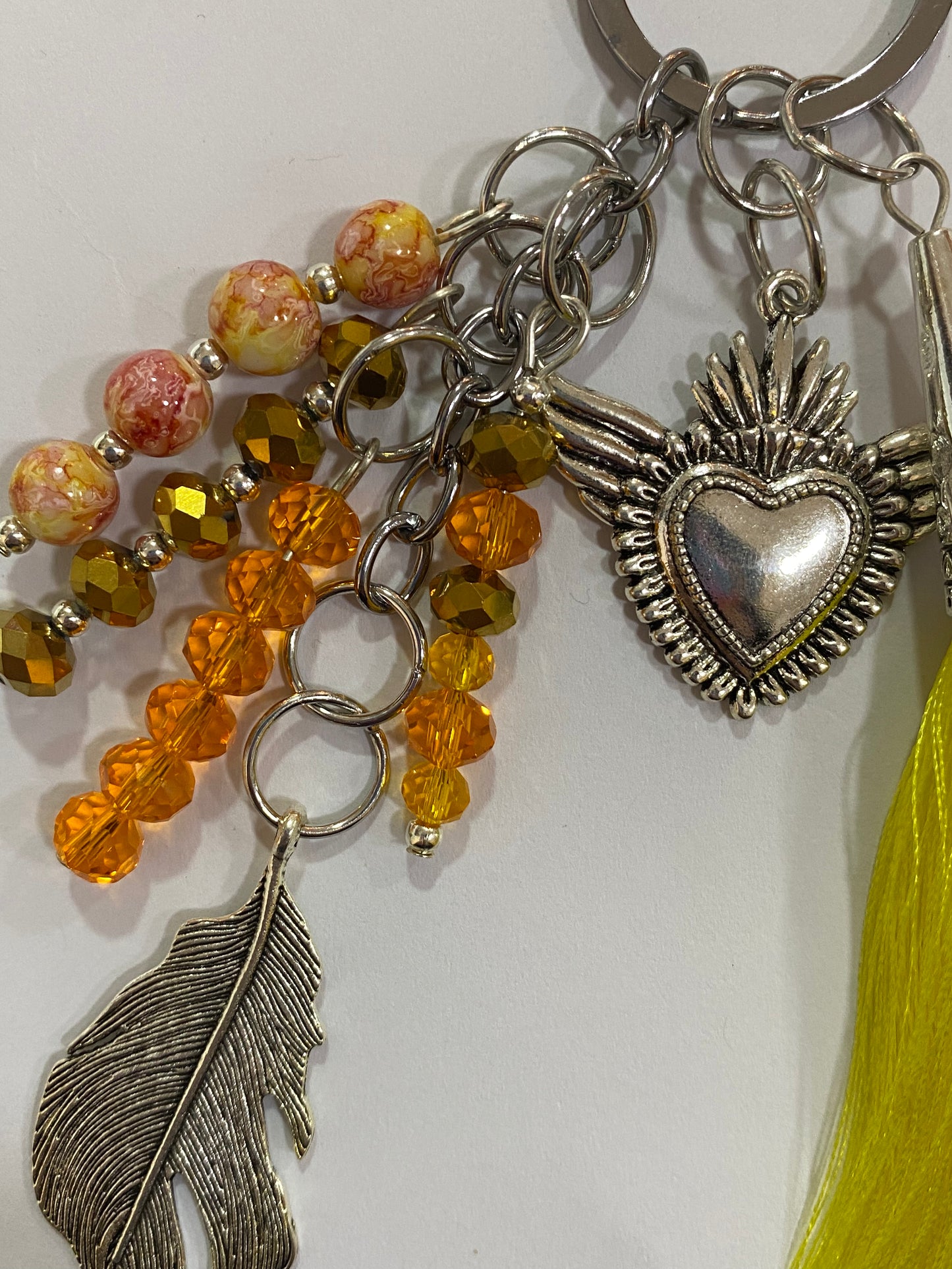 Llavero en tonos amarillos con corazón y pluma plateados