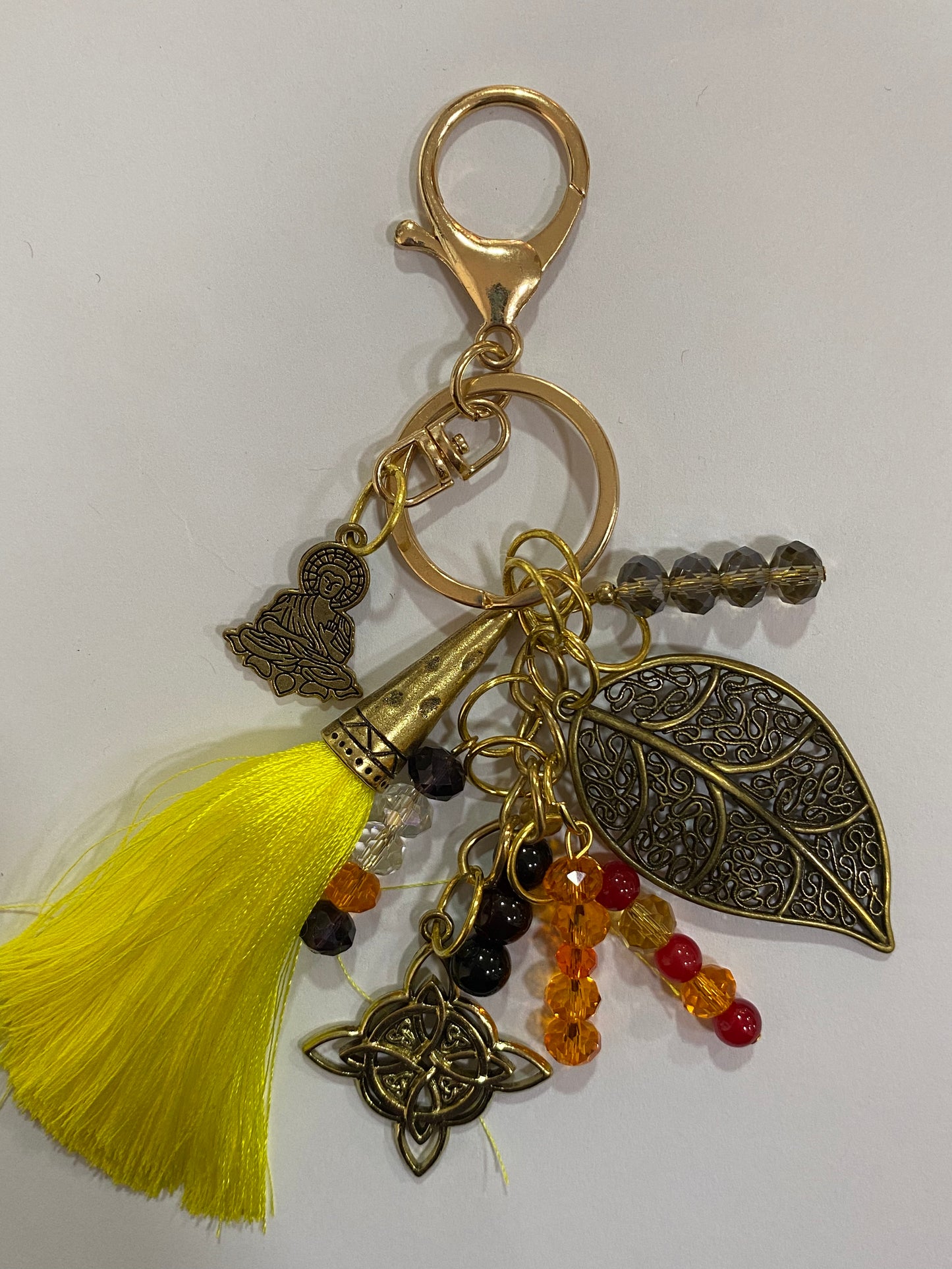 Llavero en tonos amarillos con hoja, nudo de bruja y buda