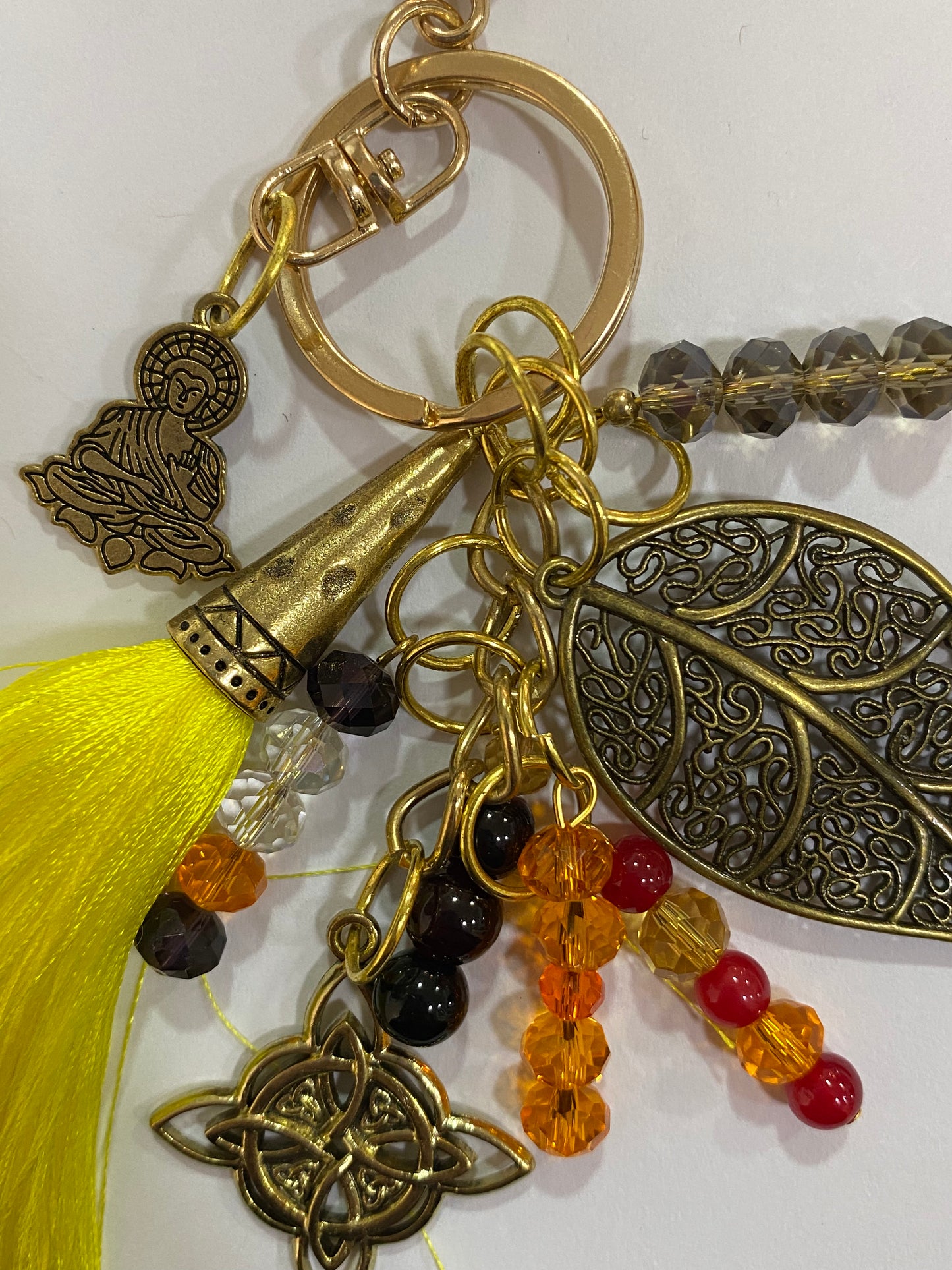 Llavero en tonos amarillos con hoja, nudo de bruja y buda