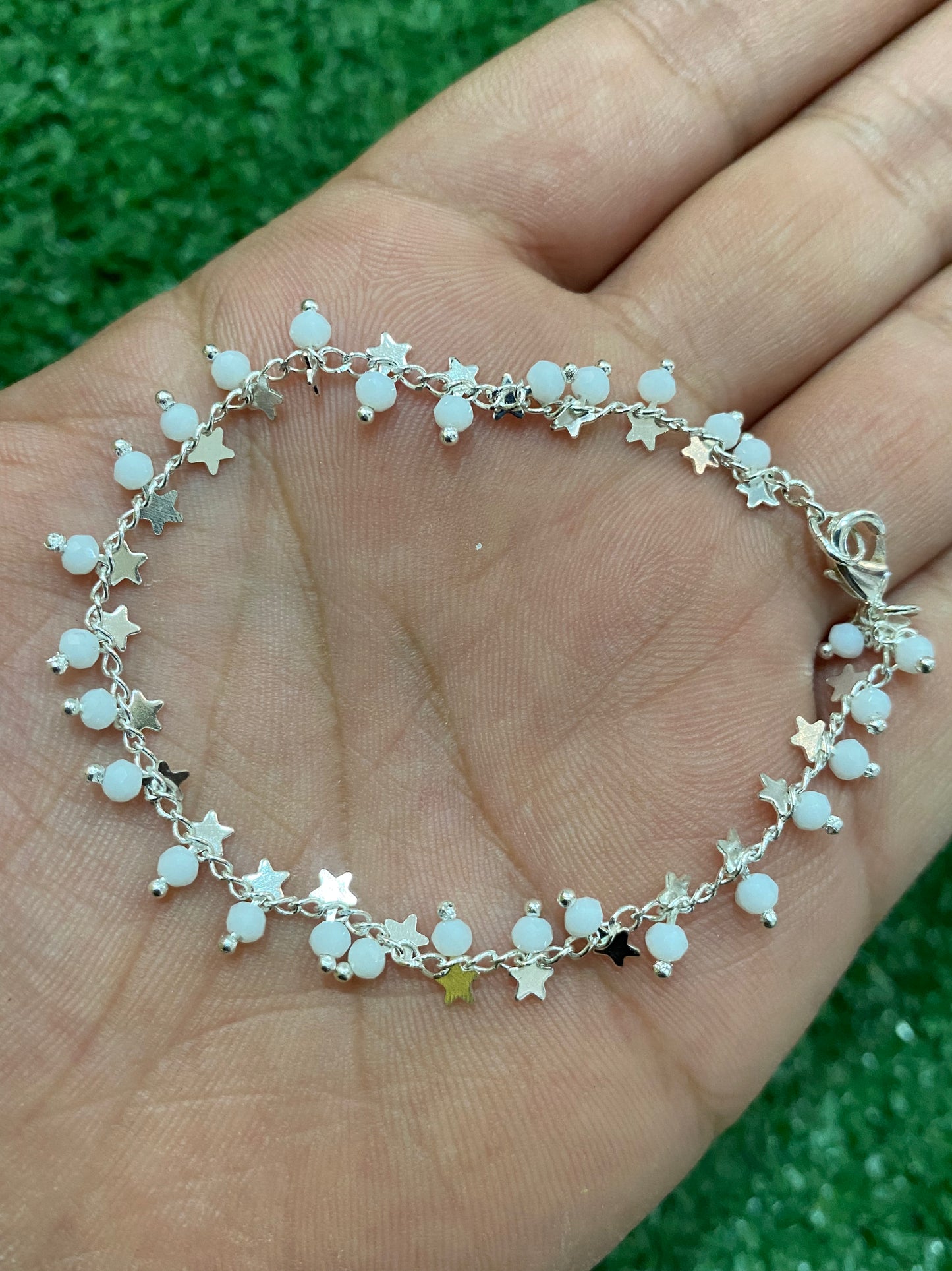 Pulsera plateada con cuentas blancas y estrellas con baño en plata
