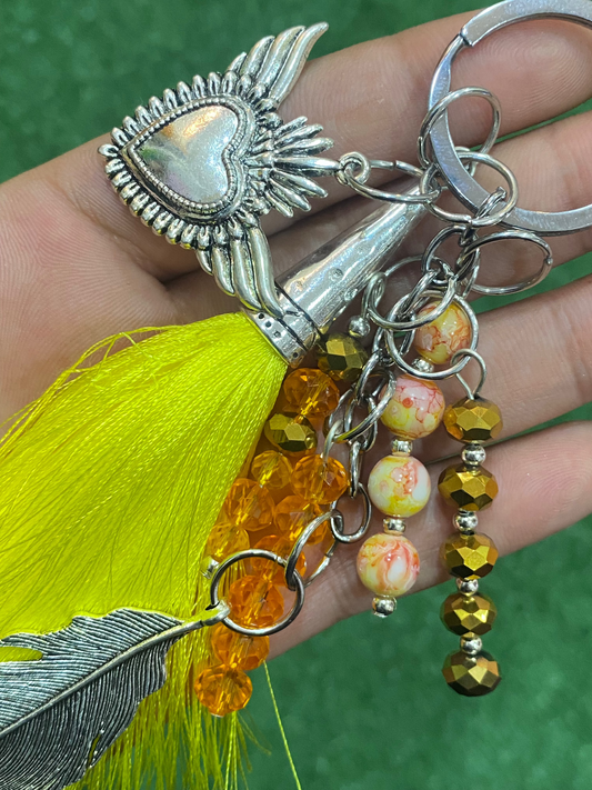 Llavero en tonos amarillos con corazón y pluma plateados