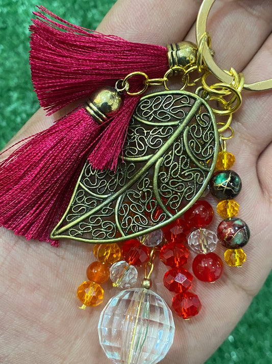 Llavero rojo con hoja central en tonos dorados