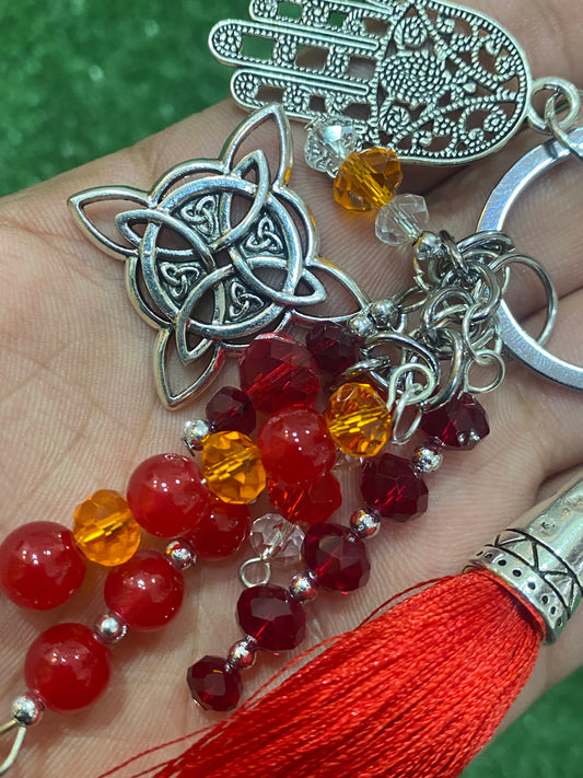 Llavero en tonos rojos con mano de Fátima y nudo de bruja plateados