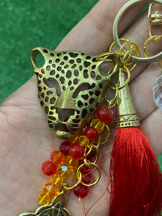 Llavero en tonos rojos con leopardo dorado, cristal y nudo de bruja