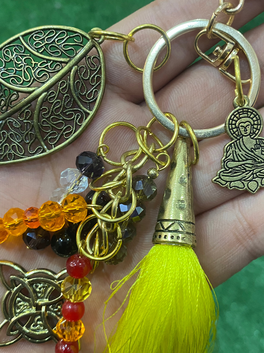 Llavero en tonos amarillos con hoja, nudo de bruja y buda