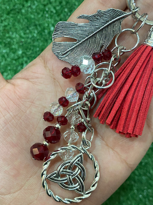 Llavero en tonos rojos con pluma y triqueta