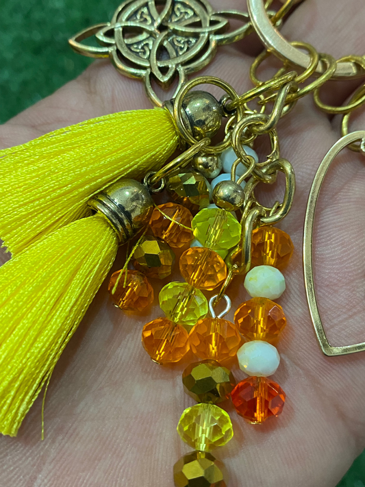 Llavero en tonos amarillos con corazón en baño de oro y nudo de bruja