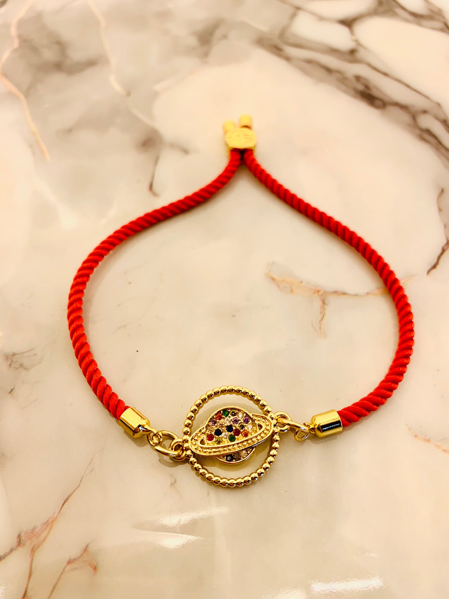 Pulsera Roja de Cordón con Terminales Baño Oro y Dije Conector de Saturno