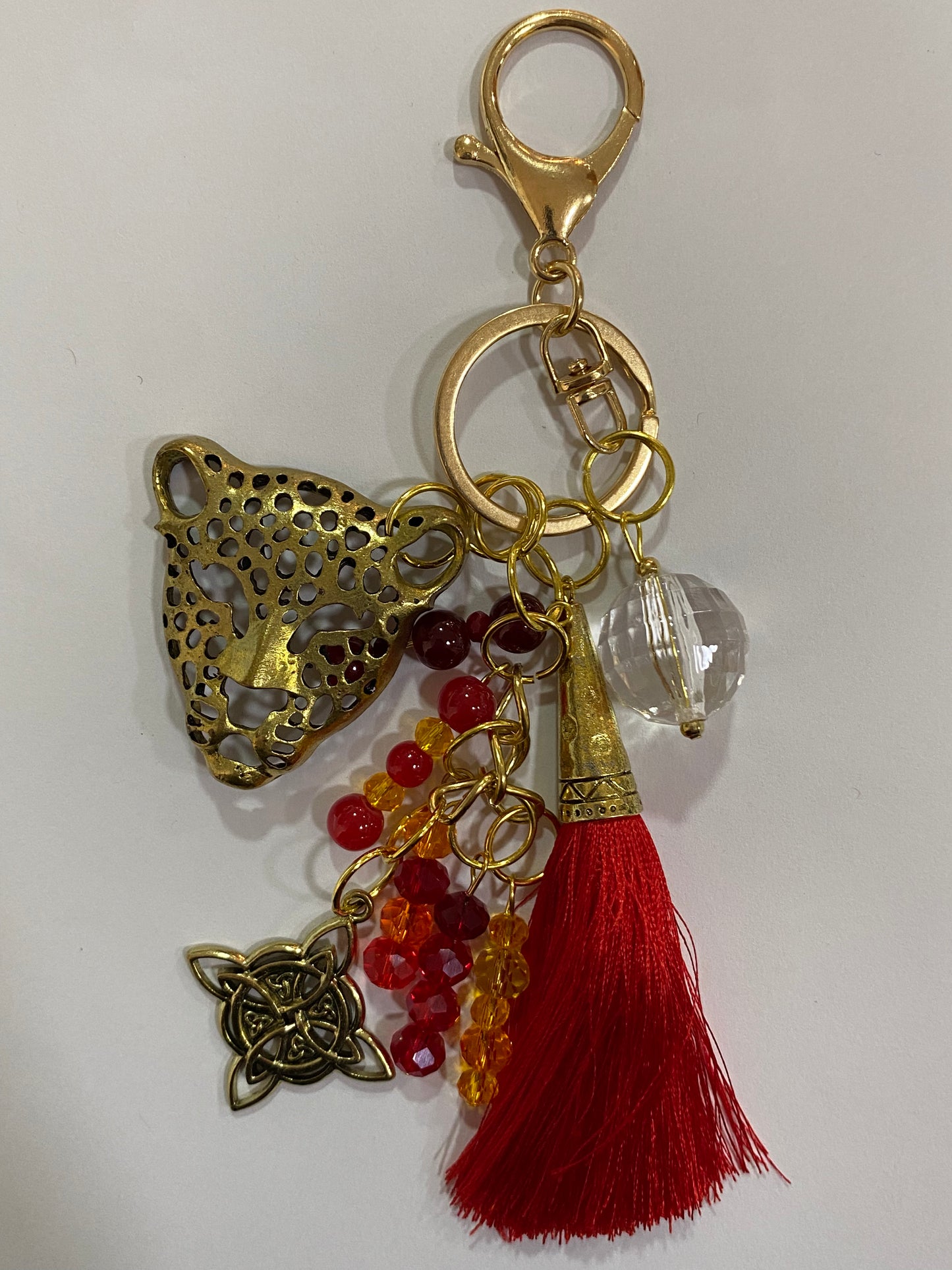 Llavero en tonos rojos con leopardo dorado, cristal y nudo de bruja