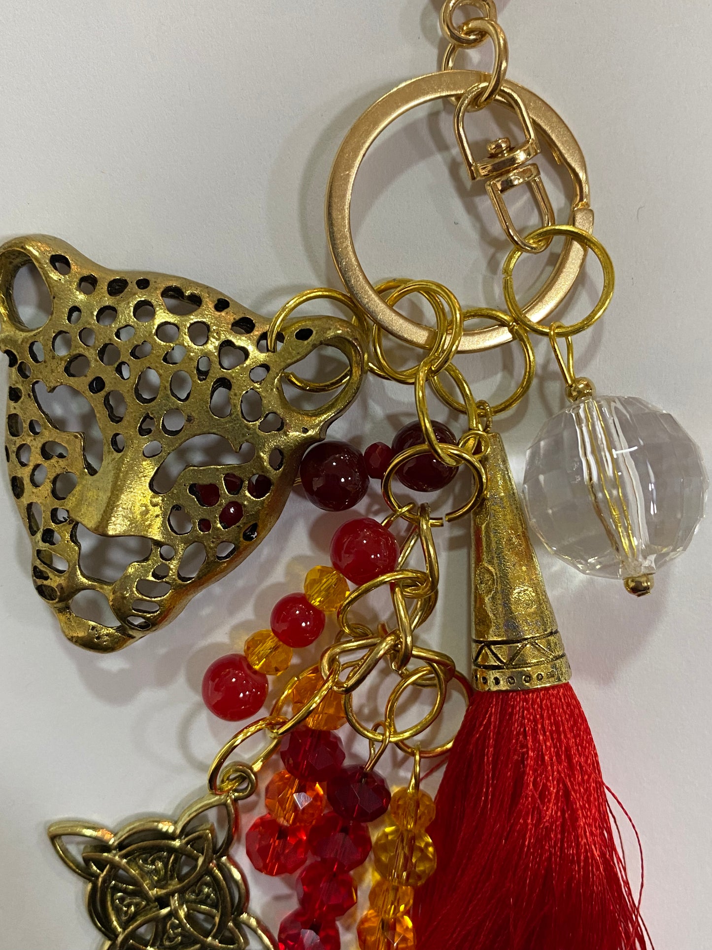 Llavero en tonos rojos con leopardo dorado, cristal y nudo de bruja