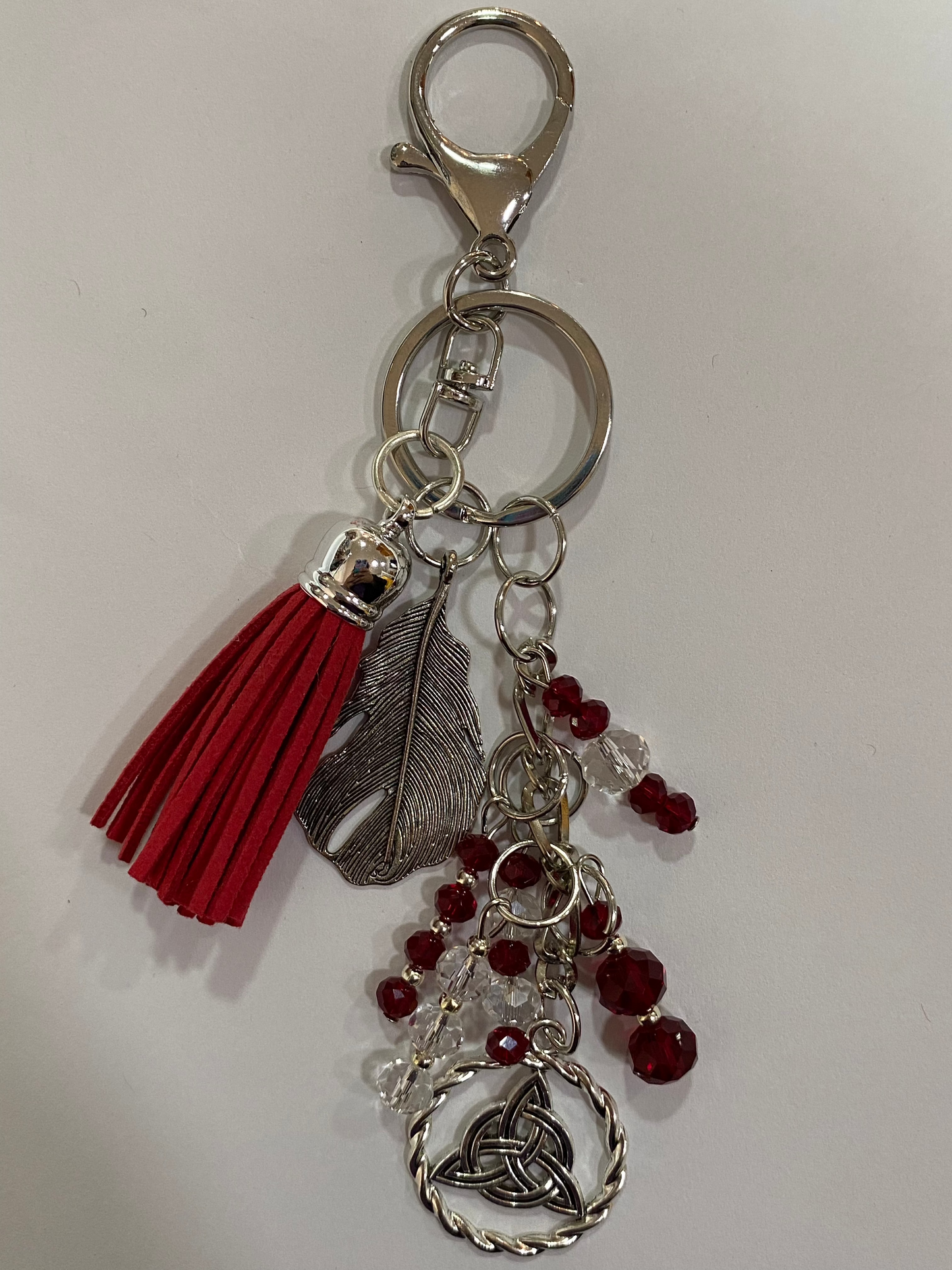 Llavero en tonos rojos con pluma y triqueta