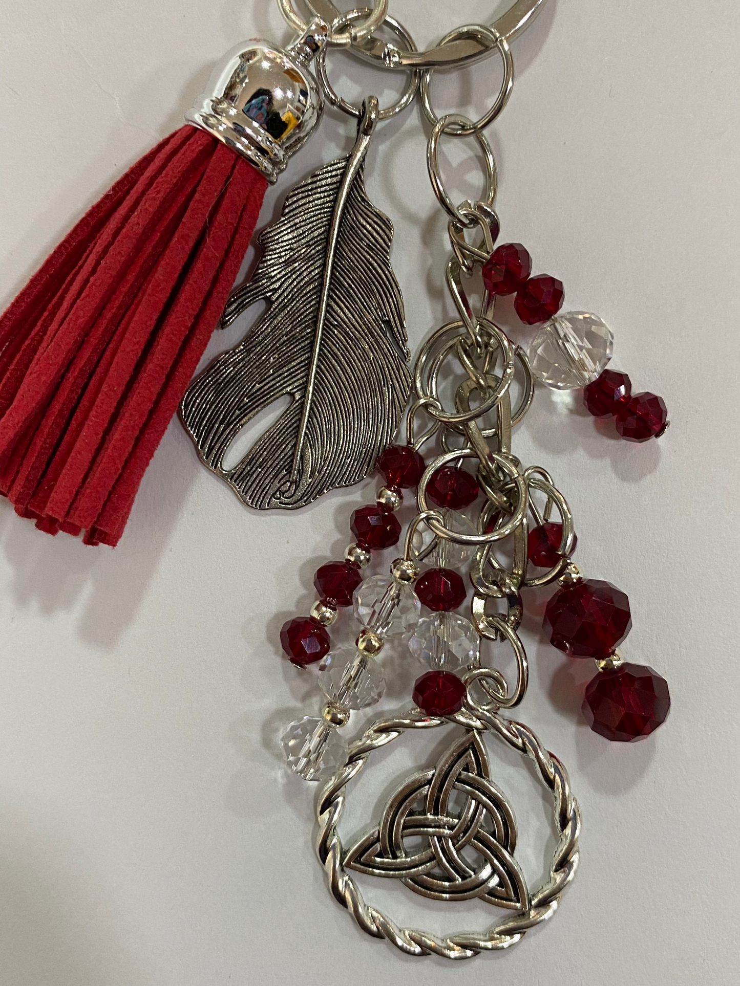 Llavero en tonos rojos con pluma y triqueta
