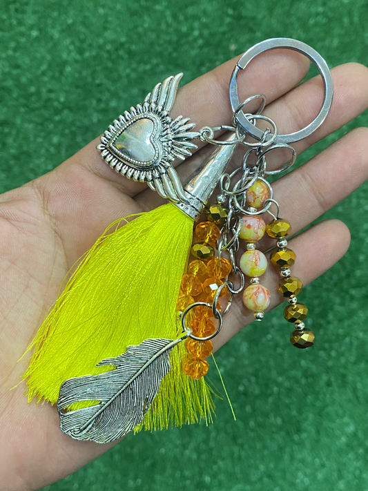 Llavero en tonos amarillos con corazón y pluma plateados