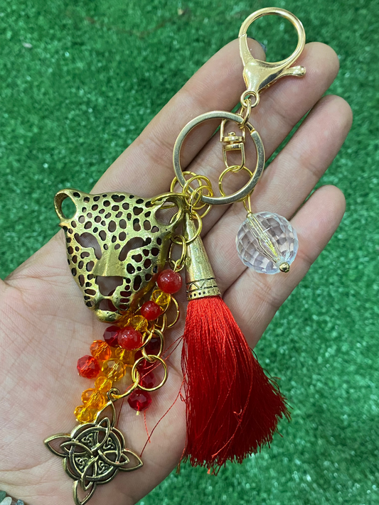 Llavero en tonos rojos con leopardo dorado, cristal y nudo de bruja