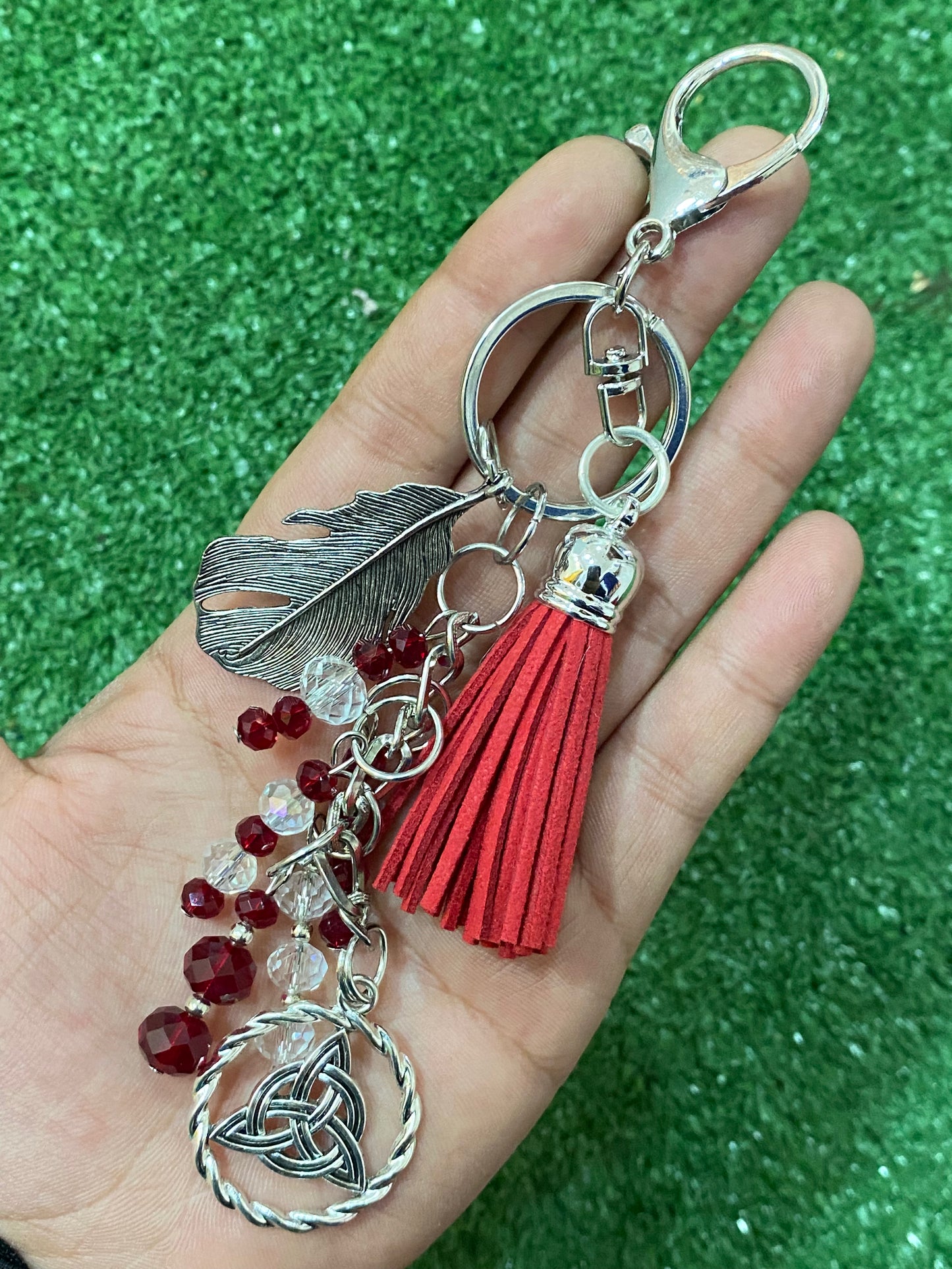 Llavero en tonos rojos con pluma y triqueta