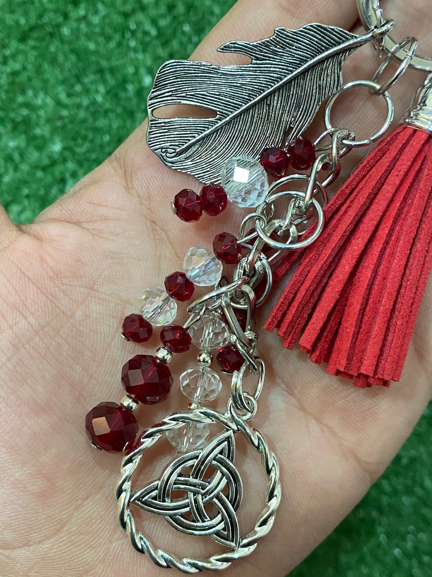 Llavero en tonos rojos con pluma y triqueta