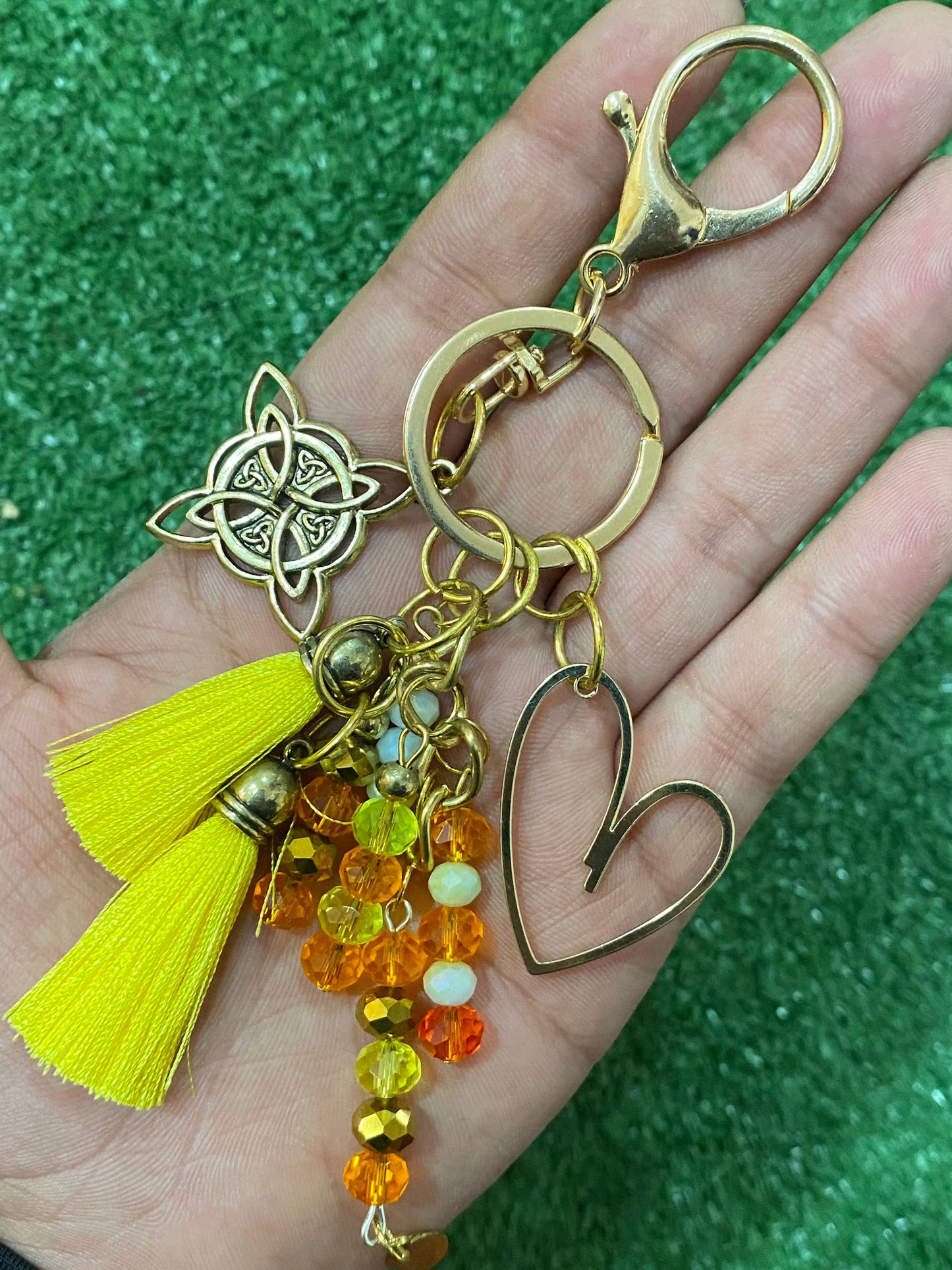 Llavero en tonos amarillos con corazón en baño de oro y nudo de bruja